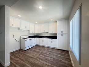 Tustin apartment for rent - A kitchen with white cabinets and a black countertop.