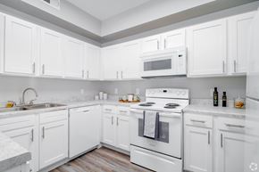 San Antonio apartment for rent - A white kitchen with a stove, sink, and cabinets.