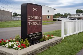 Defiance apartment for rent - A sign for Winthrop Terrace Apartment Homes stands in front of a white fence.
