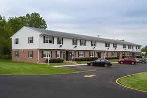Bryan apartment for rent - A black car is parked in a parking lot in front of a white building.