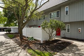 Toledo apartment for rent - A grey building with a red door and a white fence.