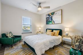 Fort Wayne apartment for rent - a bedroom with a bed and a chair and a ceiling fan at 41 North Apartments, Indiana, 46835