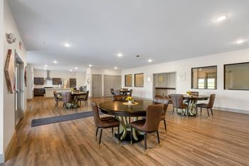 A large community room with a dining area and a kitchen with a table and chairs