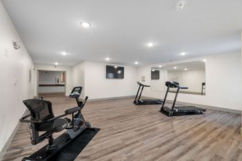 A gym with two exercise machines and a tv on the wall