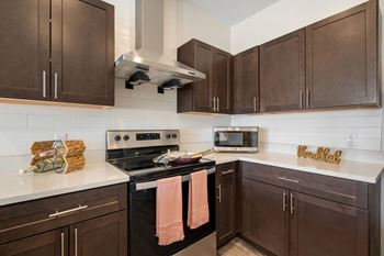 A kitchen with brown cabinets and stainless steel appliances and white countertops