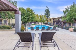 Rancho Cucamonga apartment for rent - Two chairs are placed on a patio in front of a pool.
