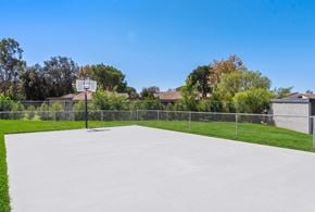 Mission Viejo apartment for rent - A basketball court surrounded by a fence with houses and trees in the background.