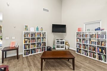 Rancho Cucamonga apartment for rent - A living room with a brown table and a bookshelf filled with books.
