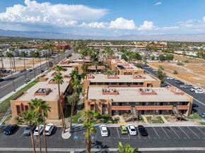 Palm Springs apartment for rent - A parking lot with a building in the background and palm trees in the foreground.