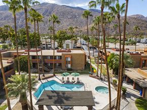 Palm Springs apartment for rent - A pool surrounded by palm trees and a mountain in the background.