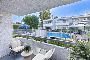 Reseda apartment for rent - A balcony with a chair and a table overlooking a pool.
