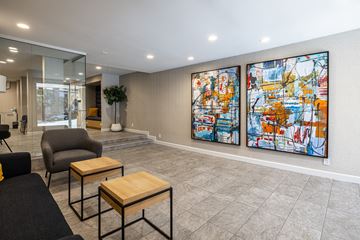 Los Angeles apartment for rent - A living room with a grey sofa, a black chair, a wooden coffee table and two large paintings on the wall.