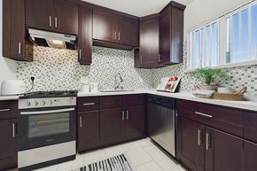 North Hollywood apartment for rent - A kitchen with dark brown cabinets and a white stove top oven.