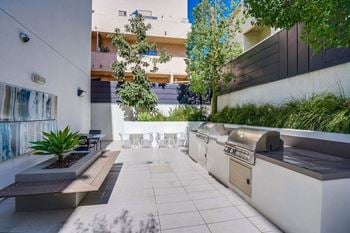 A modern outdoor patio with a bench, table, and plants.