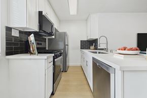 Van Nuys apartment for rent - A modern kitchen with white cabinets and black appliances.