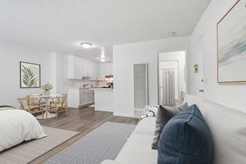 Van Nuys apartment for rent - A living room with a grey couch and a dining table.