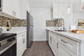 Van Nuys apartment for rent - A kitchen with a black stove top oven and white cabinets.