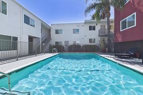 Van Nuys apartment for rent - A swimming pool in front of a white and red building.