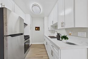North Hills apartment for rent - A kitchen with white cabinets and a black refrigerator.