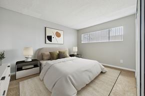 North Hills apartment for rent - A bedroom with a large bed and a nightstand with a lamp.