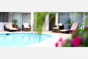 Los Angeles apartment for rent - A pool with chairs and plants around it.