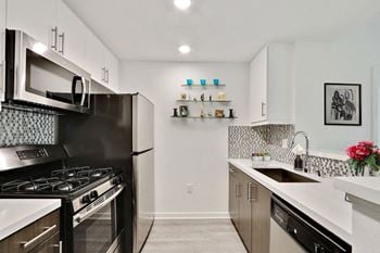 A modern kitchen with black and white appliances and a tiled backsplash.