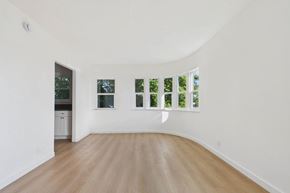 Los Angeles apartment for rent - A white room with a wooden floor and a window with a view of trees.