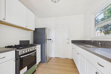 Los Angeles apartment for rent - A kitchen with white cabinets and a black stove top oven.