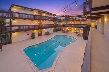 Torrance apartment for rent - A large outdoor swimming pool surrounded by a patio area with lights strung above.