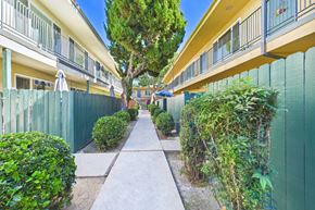 Canoga Park apartment for rent - A long, narrow walkway separates two rows of green fences and houses.