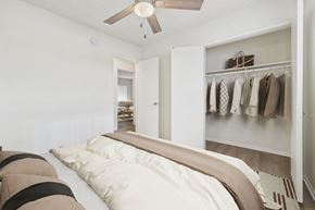 Canoga Park apartment for rent - A bedroom with a bed and a closet with clothes hanging.