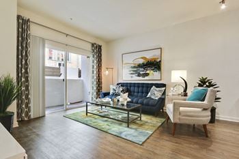 A living room with a blue couch and a painting on the wall.