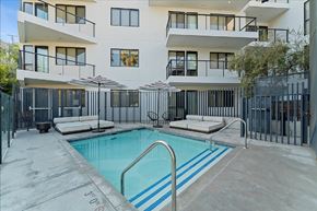 Los Angeles apartment for rent - A swimming pool in front of a white building with black railings.