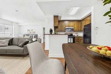 Los Angeles apartment for rent - A modern kitchen with a wooden island and a dining table with a bowl of fruit on it.