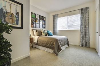 A bedroom with a bed, a guitar picture, a window with curtains, and a carpet.