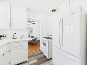 Santa Monica apartment for rent - A white LG refrigerator stands in a kitchen with white cabinets and a wooden floor.