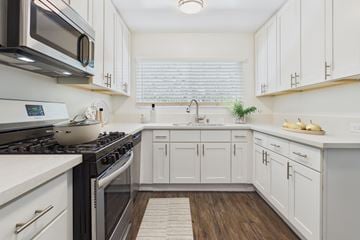 Studio City apartment for rent - A kitchen with white cabinets and a black stove top.