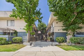 Sherman Oaks apartment for rent - A white building with a black gate and a tree in front.