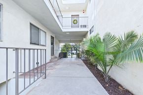 Burbank apartment for rent - A long concrete walkway with a metal railing on the left and a green plant on the right.