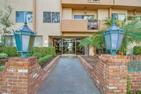 Los Angeles apartment for rent - A building entrance with a brick wall and two green lamps.