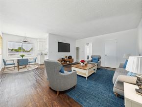 Santa Monica apartment for rent - A living room with a grey sofa, a grey armchair, a wooden coffee table, and a flat screen TV mounted on the wall.
