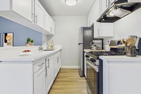North Hills apartment for rent - A kitchen with white cabinets and a black refrigerator.