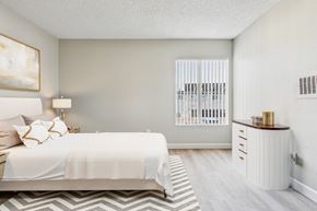 North Hills apartment for rent - A bedroom with a large bed and a nightstand with a lamp.