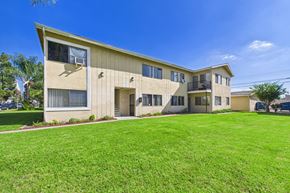 Garden Grove apartment for rent - A beige building with a green lawn in front.