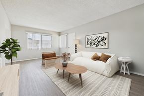 Garden Grove apartment for rent - A living room with a white couch, a wooden coffee table, and a large plant.