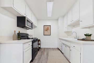 Bellflower apartment for rent - A kitchen with white cabinets and a black stove top oven.