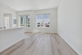 Culver City apartment for rent - A spacious room with wooden flooring and a large window overlooking a cityscape.