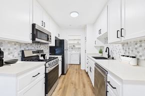 Pasadena apartment for rent - A kitchen with white cabinets and black appliances.