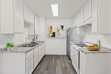 Bellflower apartment for rent - A kitchen with white cabinets and a marble countertop.