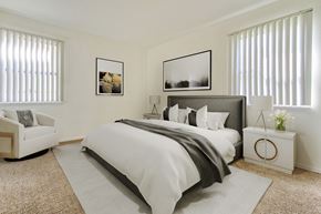 Long Beach apartment for rent - A bedroom with a large bed, a white armchair, and two framed pictures on the wall.